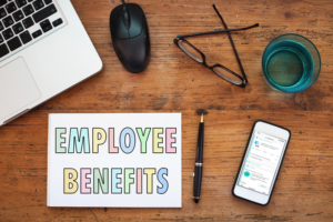 A sign reading employee benefits with a computer and phone shown on a desk