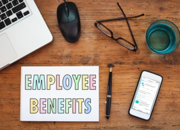 A sign reading employee benefits with a computer and phone shown on a desk