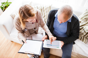 Female nurse helping an elderly man fill out a health assessment