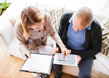 Female nurse helping an elderly man fill out a health assessment