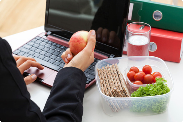 Eating a healthy lunch while working on a laptop