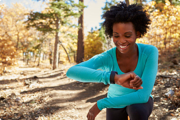 Women Running In Forest Looking At Smartwatch