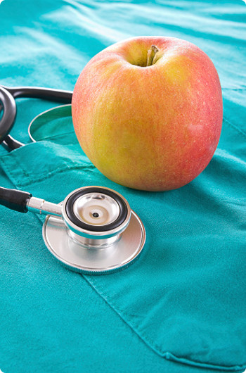 Apple and stethoscope laying on nurses scrubs