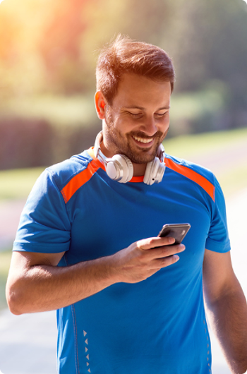 Man in exercise clothing connecting his headphones to his phone