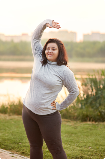 Young women stretching by the lake at sunrise