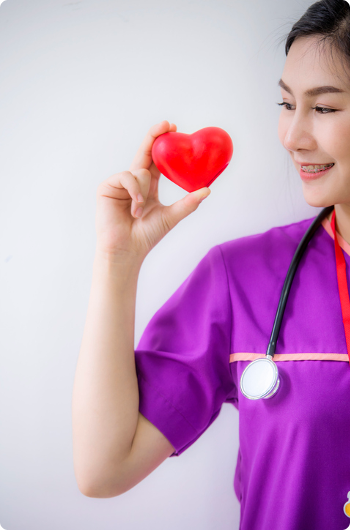 Young women in bright purplse scrubs holding up a plastic heart