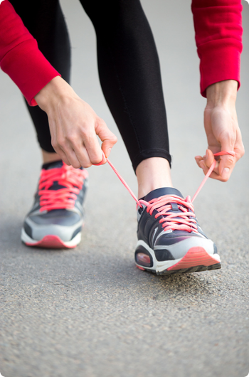 Tying red laced shoes in the street