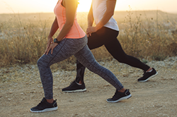 A man and women doing lunges at sunset