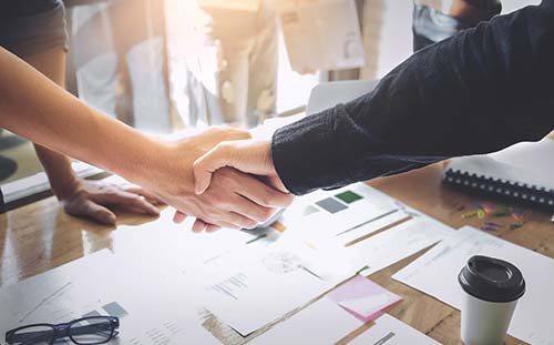 Two people shaking hands at an office desk