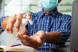  Male employee wear health mask washing hand with alcohol gel to prevent corona virus covid-19 infection, concept of working from home or WFH and social or physical distancing. 