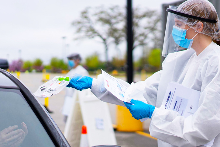 Car driving up and being handed a testing kit