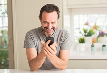 Happy man looking down at cell phone