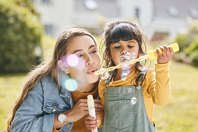 Women and child outside blowing bubbles