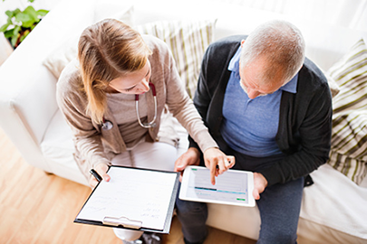 Female nurse helping an elderly man complete a health assessment on a tablet